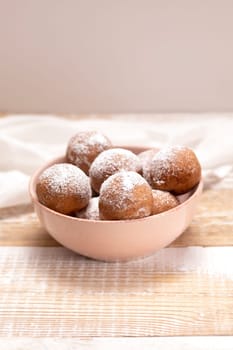 Paczki Or Zeppole In Pink Bowl With Powdered Sugar On Wooden Table. Fat Thursday Carnival or Tlusty Czwartek, Christian tradition Of Eating Doughnut, Delicious Donuts. Vertical Plane