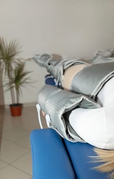 Closeup pressure therapy procedure. Woman lying in massaging suit in hospital, treatment of varicose veins, edema, lymphatic drainage, weight loss. Relaxation,cure. Pressotherapy concept. Vertical