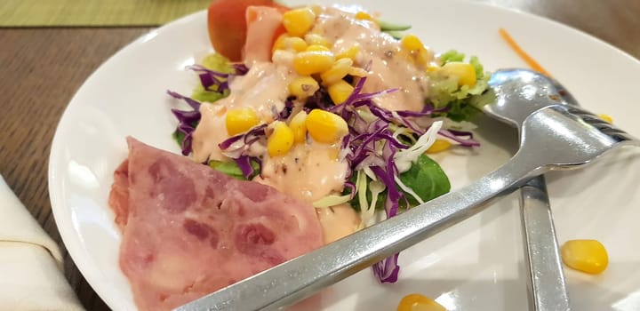 delicious breakfast, ham and fresh summer salad on white plate, on wooden table, view from above, good for your multimedia content background