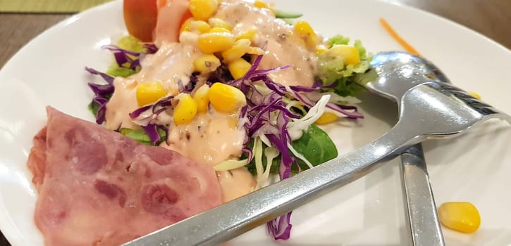 delicious breakfast, ham and fresh summer salad on white plate, on wooden table, view from above, good for your multimedia content background