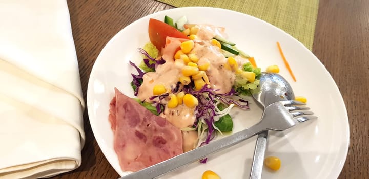 delicious breakfast, ham and fresh summer salad on white plate, on wooden table, view from above, good for your multimedia content background