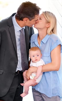 Love, family and parents kiss with baby, bonding or affection at home on valentines day. Child, toddler or mother with father in romance for connection, care or healthy relationship together in house.