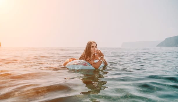 Woman summer sea. Happy woman swimming with inflatable donut on the beach in summer sunny day, surrounded by volcanic mountains. Summer vacation concept