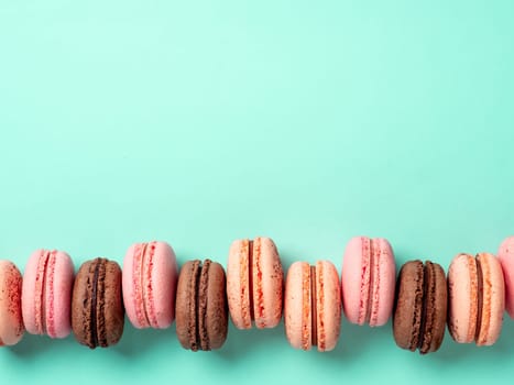 Macarons with copy space. Row of perfect french macarons or macaroons on blue turquoise background. Top view or flat lay