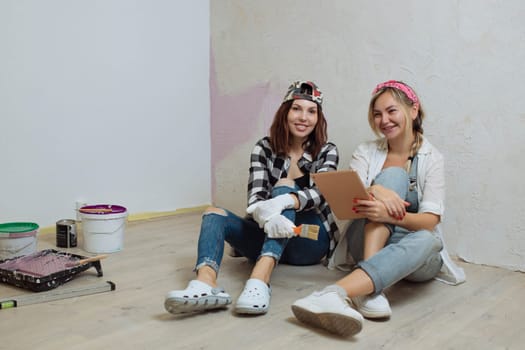 Home interior. Two cute girls designer and painter make repairs in the house.A team of decorators.