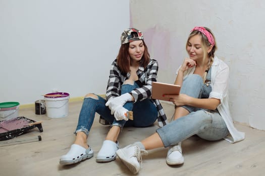 Home interior. Two cute girls designer and painter make repairs in the house.A team of decorators.