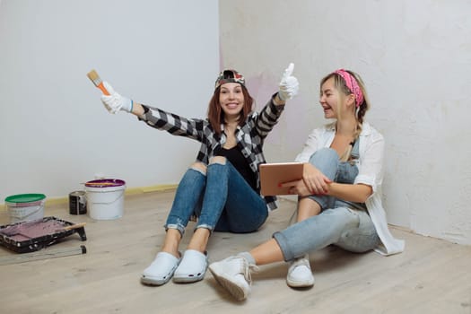 Home interior. Two cute girls designer and painter make repairs in the house.A team of decorators.