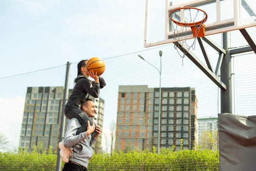 Happy father and teen daughter outside at basketball court