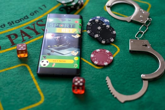 Law and rules for online casino concept, smartphone with handcuffs and playing chips.
