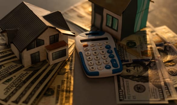 paper houses, money and calculator stands over a wooden background