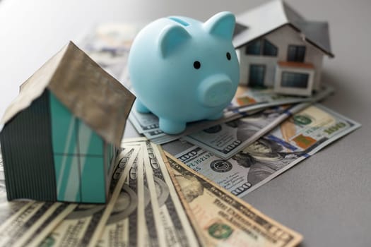 piggy bank for money and a house model with dollars on a white background. buying a property. the concept of buying and selling houses and apartments