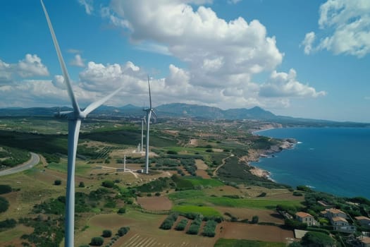 Aerial view of towering wind turbines dotting the rural landscape near a coastal area, showcasing a harmonious blend of technology and nature. The windmills stand as sentinels of sustainable energy against a backdrop of cultivated fields and deep blue sea