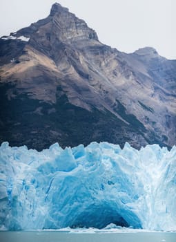 Glacier's vivid blue ice set against a contrasting dark mountain backdrop.