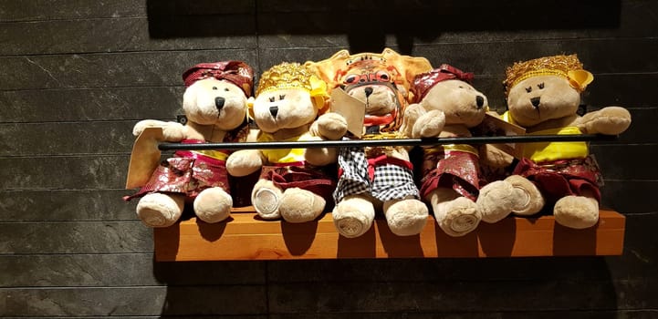 Group of Fluffy Stuffed Bear Toys Wearing various Clothes, teddy bear stuffed animal sitting in the wood bracket