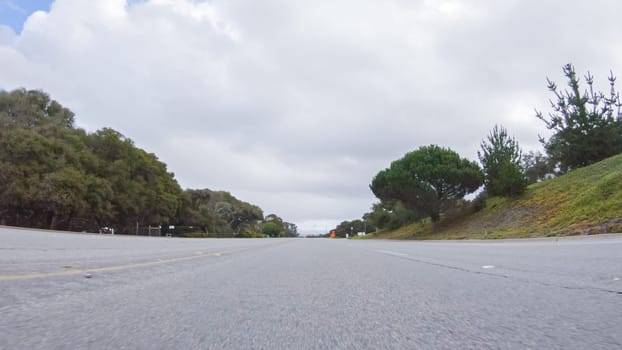 Vehicle navigates the streets of Morro Bay, California, during a cloudy winter day. The atmosphere is moody and serene as the overcast sky casts a soft light on the charming buildings and quiet streets of this coastal town.