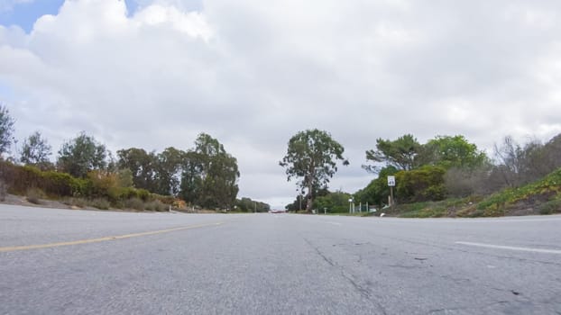 Vehicle navigates the streets of Morro Bay, California, during a cloudy winter day. The atmosphere is moody and serene as the overcast sky casts a soft light on the charming buildings and quiet streets of this coastal town.