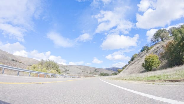 Vehicle is cruising along the Cuyama Highway under the bright sun. The surrounding landscape is illuminated by the radiant sunshine, creating a picturesque and inviting scene as the car travels through this captivating area.