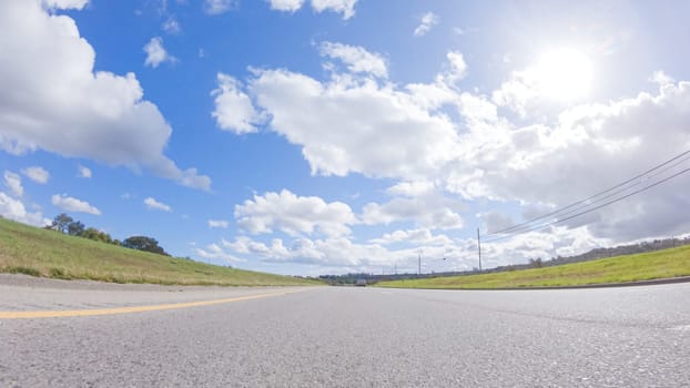 On a clear winter day, a car smoothly travels along Highway 101 near Santa Maria, California, under a brilliant blue sky, surrounded by a blend of greenery and golden hues.