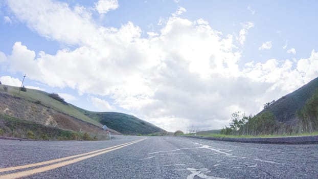 Vehicle is cruising along the Cuyama Highway under the bright sun. The surrounding landscape is illuminated by the radiant sunshine, creating a picturesque and inviting scene as the car travels through this captivating area.