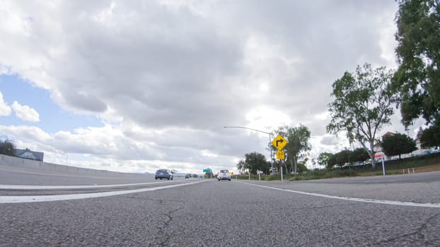 On a cloudy winter day, a car smoothly travels along Highway 101 near Santa Maria, California, under a cloudy sky, surrounded by a blend of greenery and golden hues.