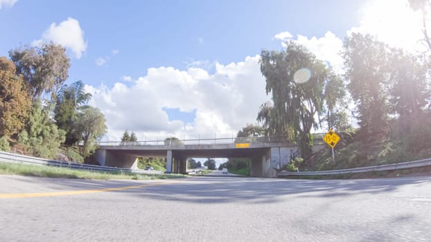 On a clear winter day, a car smoothly travels along Highway 101 near Santa Maria, California, under a brilliant blue sky, surrounded by a blend of greenery and golden hues.