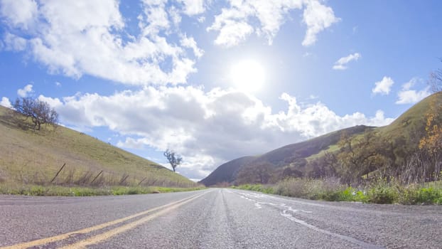 Vehicle is cruising along the Cuyama Highway under the bright sun. The surrounding landscape is illuminated by the radiant sunshine, creating a picturesque and inviting scene as the car travels through this captivating area.