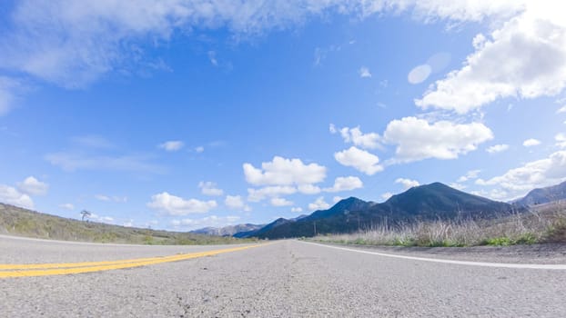 Vehicle is cruising along the Cuyama Highway under the bright sun. The surrounding landscape is illuminated by the radiant sunshine, creating a picturesque and inviting scene as the car travels through this captivating area.