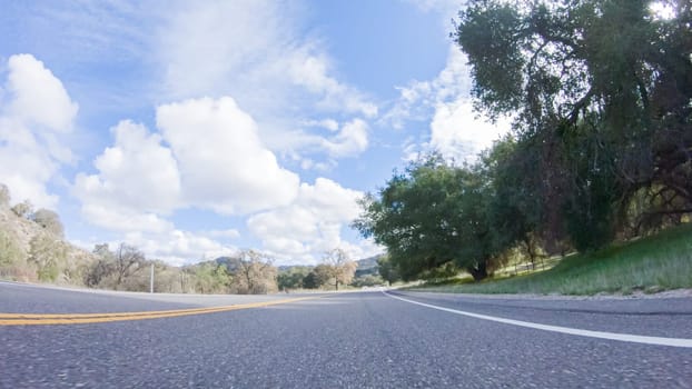 Vehicle is cruising along the Cuyama Highway under the bright sun. The surrounding landscape is illuminated by the radiant sunshine, creating a picturesque and inviting scene as the car travels through this captivating area.