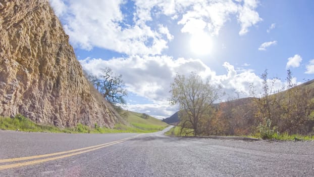 Vehicle is cruising along the Cuyama Highway under the bright sun. The surrounding landscape is illuminated by the radiant sunshine, creating a picturesque and inviting scene as the car travels through this captivating area.