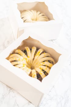 The freshly baked bundt cakes are carefully nestled into white paper boxes, preparing them for secure transportation while maintaining their delectable appearance.