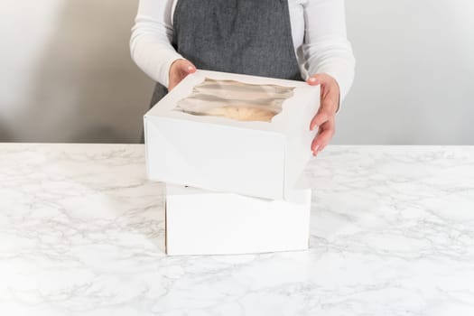 The freshly baked bundt cakes are carefully nestled into white paper boxes, preparing them for secure transportation while maintaining their delectable appearance.