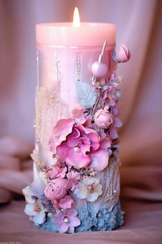 Decorative candle with pink flowers, beads, and rustic wood base.