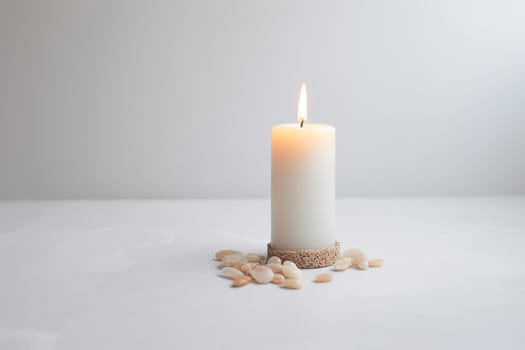A single lit candle surrounded by small pebbles on a plain background.