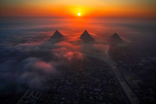 Aerial view of sunset over mountains with clouds in the foreground.