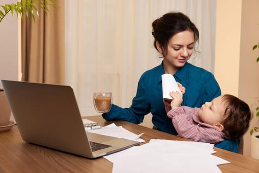 beautiful businesswoman working on laptop with her little child girl at home