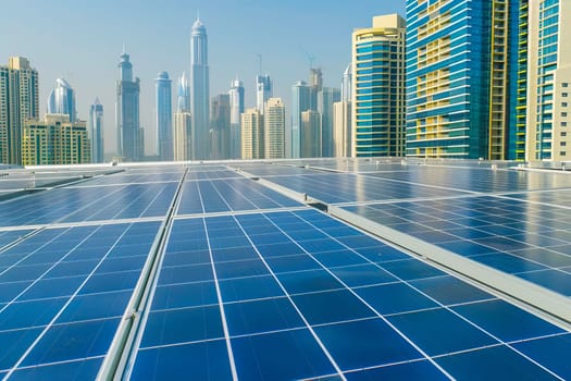 Solar panels on a buildings roof with urban skyscrapers visible in the background.