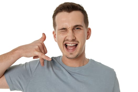 young smiling man showing phone gesture on white background. call me