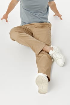guy with crossed leg wearing white sneakers and beige pants sitting on floor
