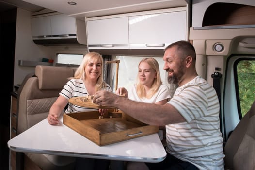 A family of three is playing a board game while sitting in a motorhome.