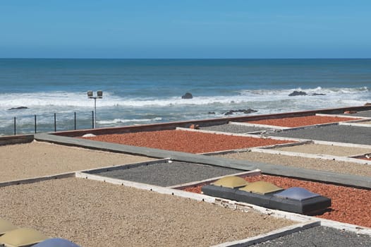 A view from above of rooftop decorated with colorful stones. Atlantic ocean beach on the background