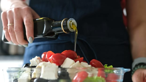 Female Hands Drizzle Oil On Greek Salad. Delicious Vegetarian Meal