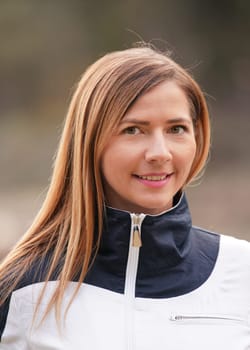 Portrait of young woman,long hair, in white sport jacket with blurred nature background