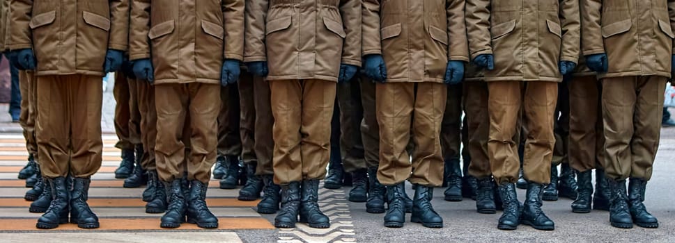 Army soldiers in uniform stand in formation on a concrete surface with yellow crosswalk lines. They wear combat fatigues and boots, showing discipline and readiness.