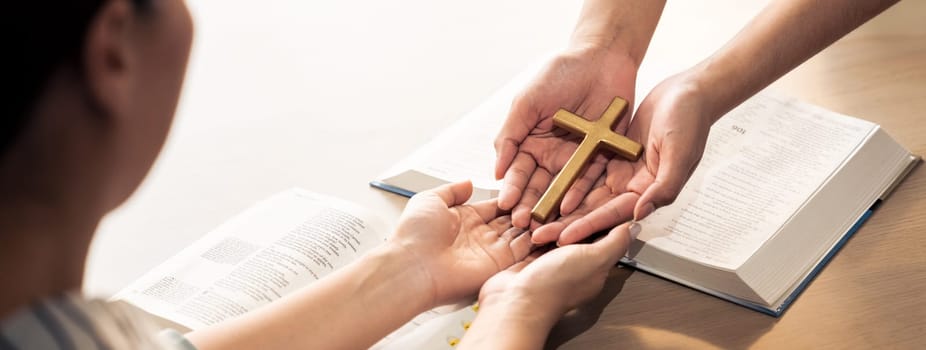 Close-up women prayer deliver holy bible book and holy cross to young believer. Spreading religion symbol. Concept of hope, religion, christianity and god blessing. Warm background. Burgeoning.