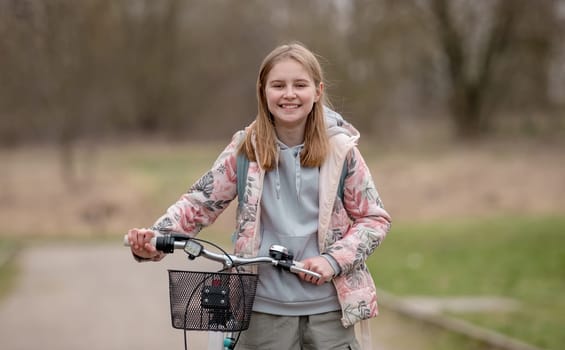Smiling Girl Holds Bicycle In Spring With Blurred Park Background