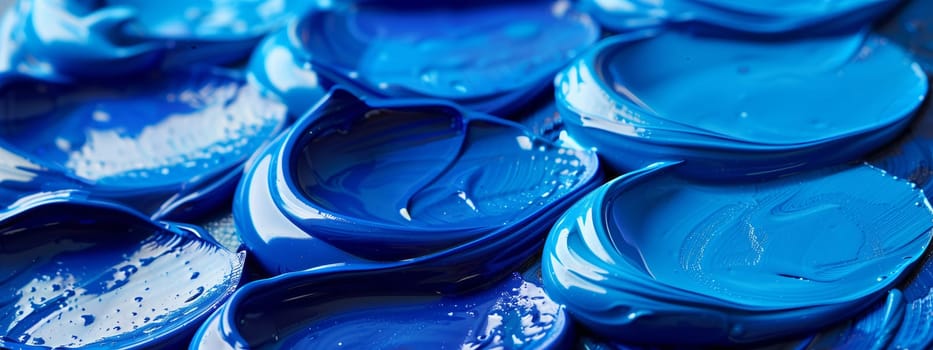 A closeup of a mound of azure liquid paint resembling a melted blue ice cube, with shades of violet and aqua blended in like petals in a fluid composition