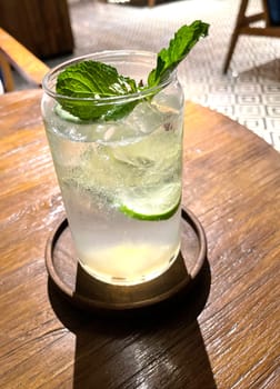 Selective focus, Delicious refreshing summer mojito with ice, lime and mint in a glass with grops. wood background. Copy space. Cold lemonade, tonic.