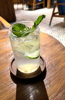 Selective focus, Delicious refreshing summer mojito with ice, lime and mint in a glass with grops. wood background. Copy space. Cold lemonade, tonic.