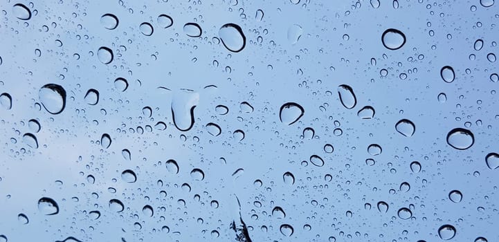 Water droplets perspective through window glass surface against blue sky good for multimedia content backgrounds