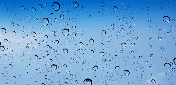 Water droplets perspective through window glass surface against blue sky good for multimedia content backgrounds